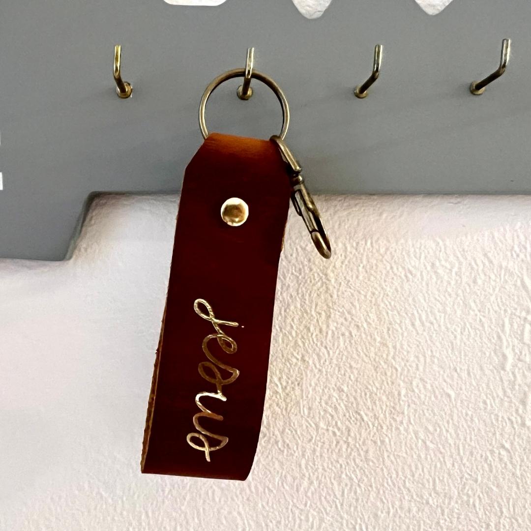 christlicher Schlüsselanhänger aus braunem Leder mit der Goldschrift "jesus"